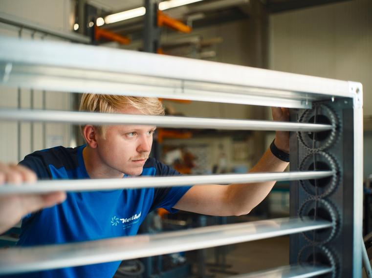 Ein junger Northoff-Mitarbeiter prüft konzentriert die Lamellen eines Lüftungselements.