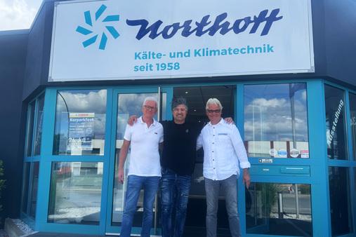 Drei Männer stehen im Eingangsbereich des Northoff Firmengebäudes mit Logo.
