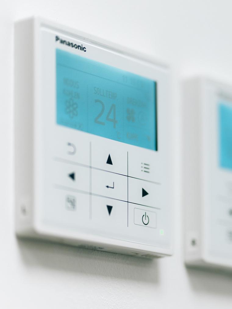 Nahaufnahme eines digitalen Panasonic Thermostats an der Wand, zeigt Raumtemperatur 24&deg;C.