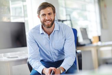 L&auml;chelnder Gesch&auml;ftsmann in Hemd sitzt im modernen B&uuml;ro. Symbolisiert Klimasysteme f&uuml;r gewerbliche B&uuml;ror&auml;ume.